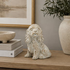 Design Republique Puppy Cement Statue in cream displayed on a wooden console with stacked books, framed artwork and decorative greenery.