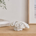 Cove Closed Coral Décor in white featuring layered textured folds displayed on a light wood surface in a coastal-inspired setting.