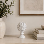 Design Republique Albinia Artichoke Small in white displayed on a neutral console beside stacked books and decorative pottery.