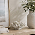 Cove Open Coral Décor in white displayed on a light wood console with neutral books, coastal artwork and a decorative vase.