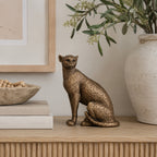 Design Republique Copper Panther statue displayed on a wooden console with neutral books, pottery and greenery.