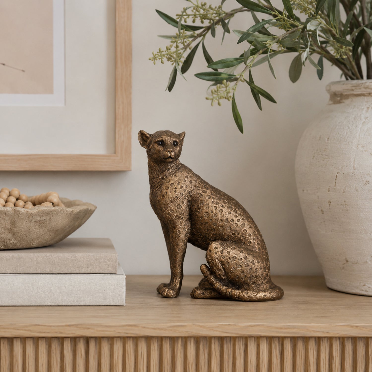 Design Republique Copper Panther statue displayed on a wooden console with neutral books, pottery and greenery.