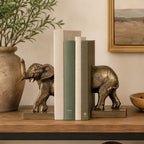 Design Republique Elephant Bookends in bronze displayed on a wooden console with neutral books and decorative foliage.