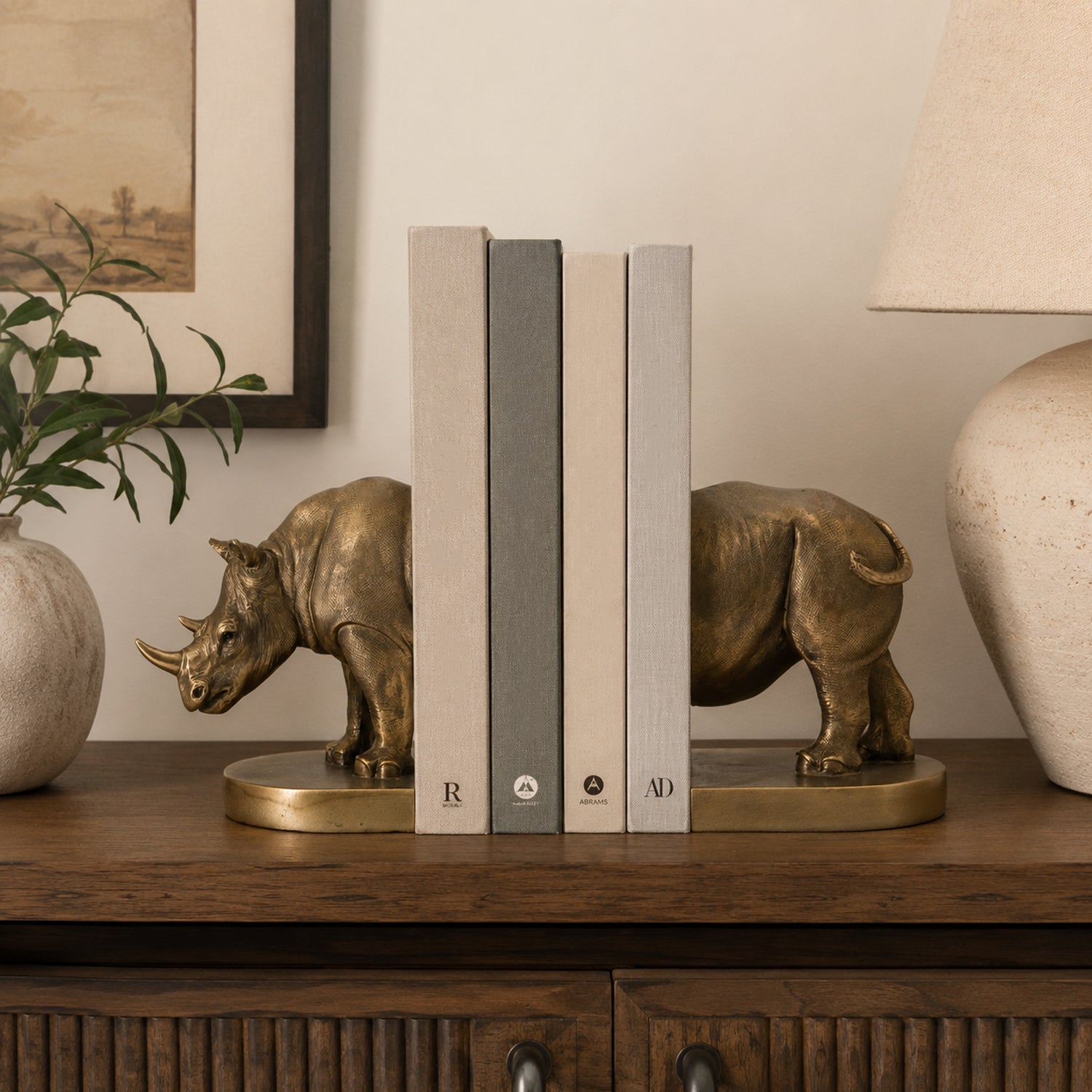 Design Republique Rhino Bronze Bookends 2 Piece Set styled on a wooden console with books between the bronze rhino design.