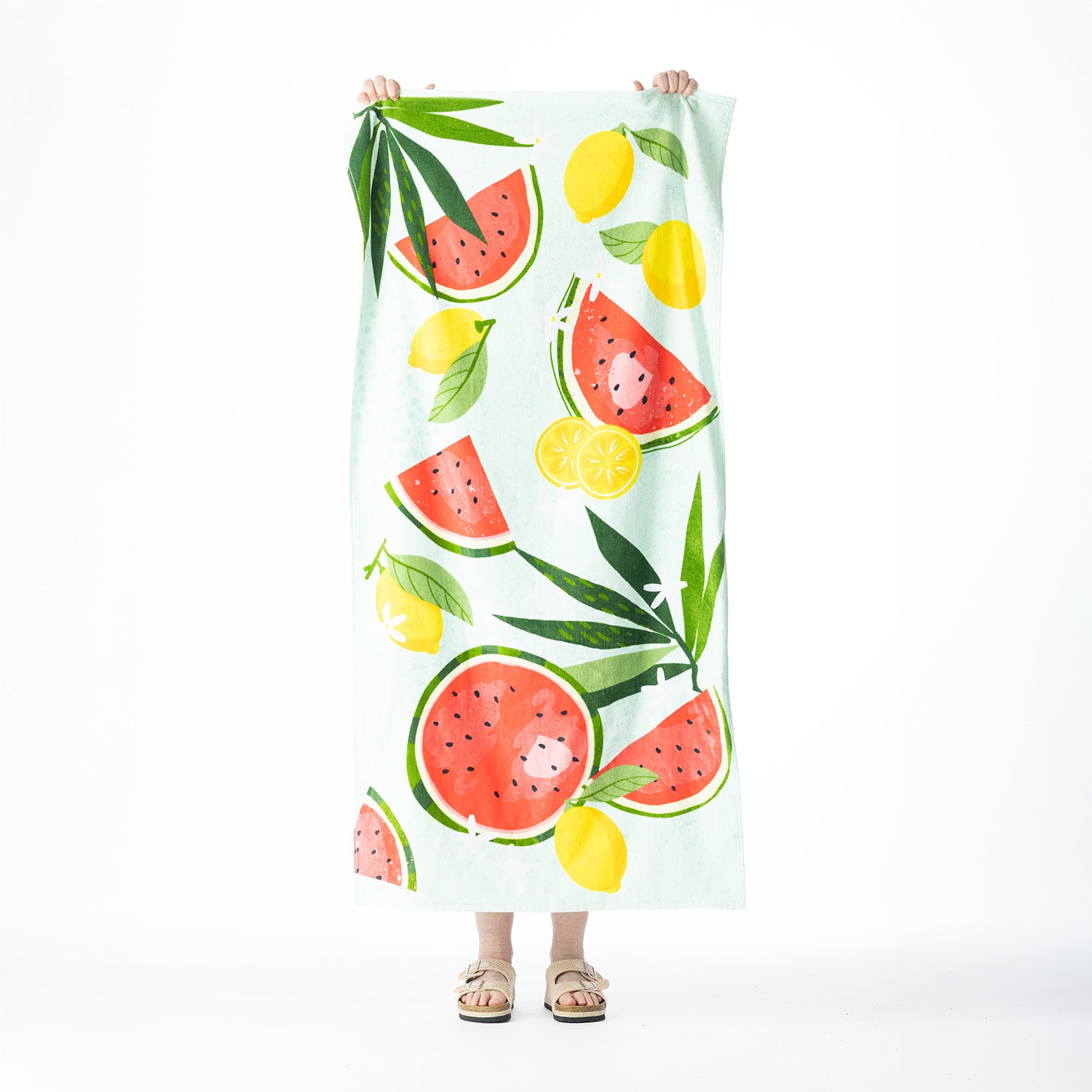 Light mint Seaside Supplies beach towel featuring a colourful watermelon, lemon and tropical leaf design, held up against a white background.
