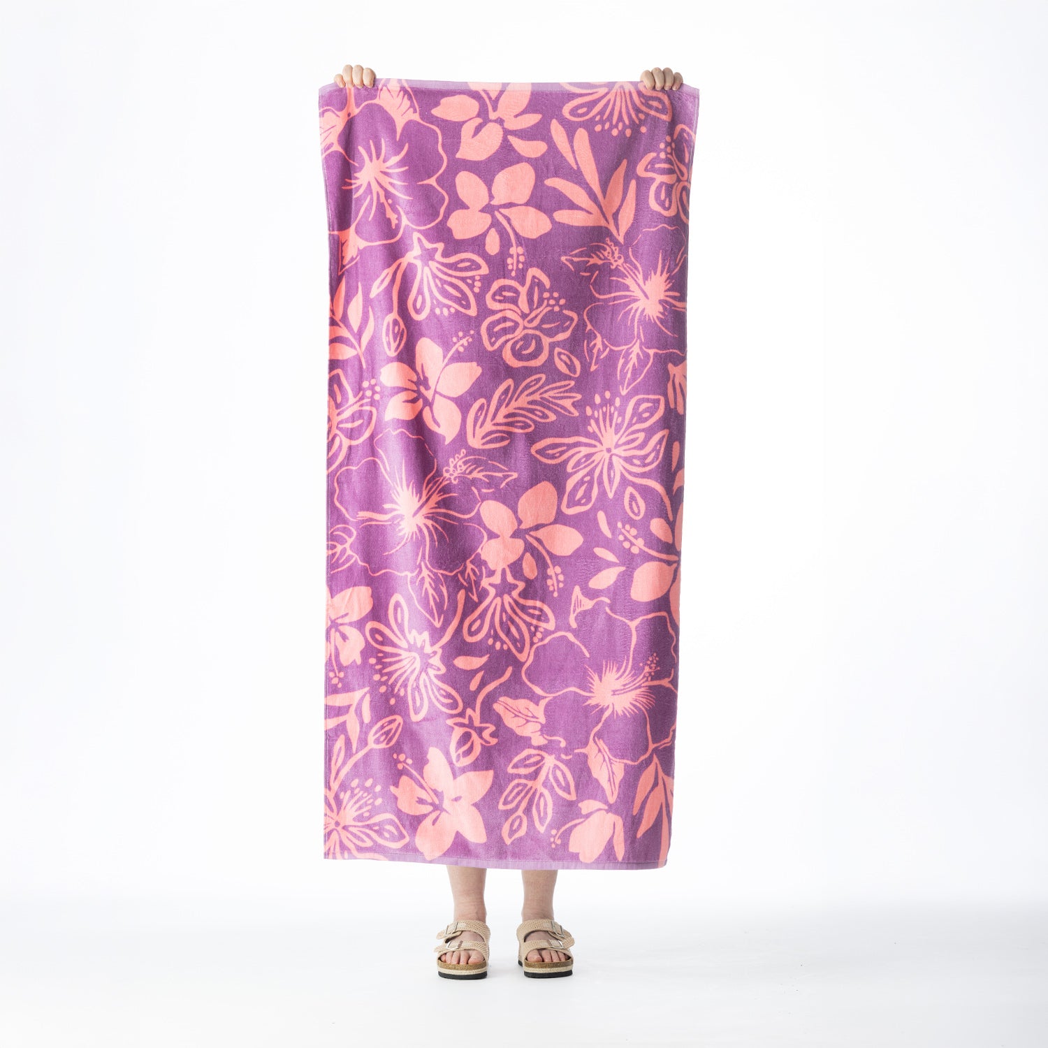 Purple Seaside Supplies beach towel featuring an all-over pink hibiscus floral print, held up against a white background.