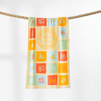 Multicoloured Surf Life Saving beach towel featuring colourful beach-themed icons and a circular Aotearoa emblem, hanging over a rope.