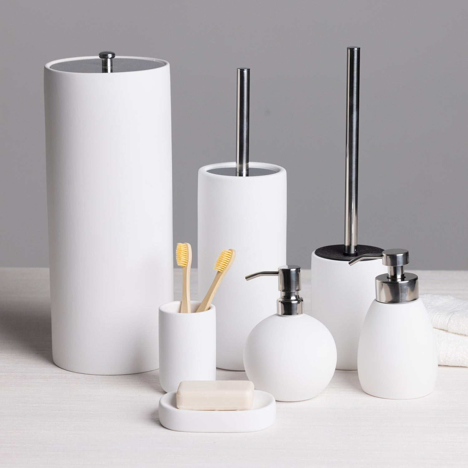 A coordinated white bathroom accessories collection, including a toilet roll holder, toilet brush, soap dispensers, toothbrush holder, and soap dish, brings a clean, modern look to any bathroom.