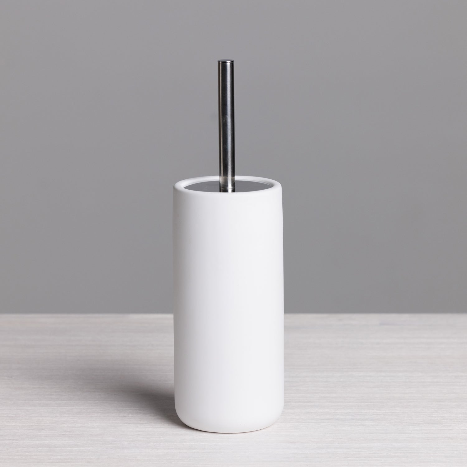 A sleek white toilet brush with a minimalist cylindrical holder and brushed stainless steel handle adds clean, contemporary style to any bathroom.