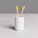 A minimalist white tumbler provides a clean and stylish holder for toothbrushes or bathroom essentials, adding a modern touch to your vanity.