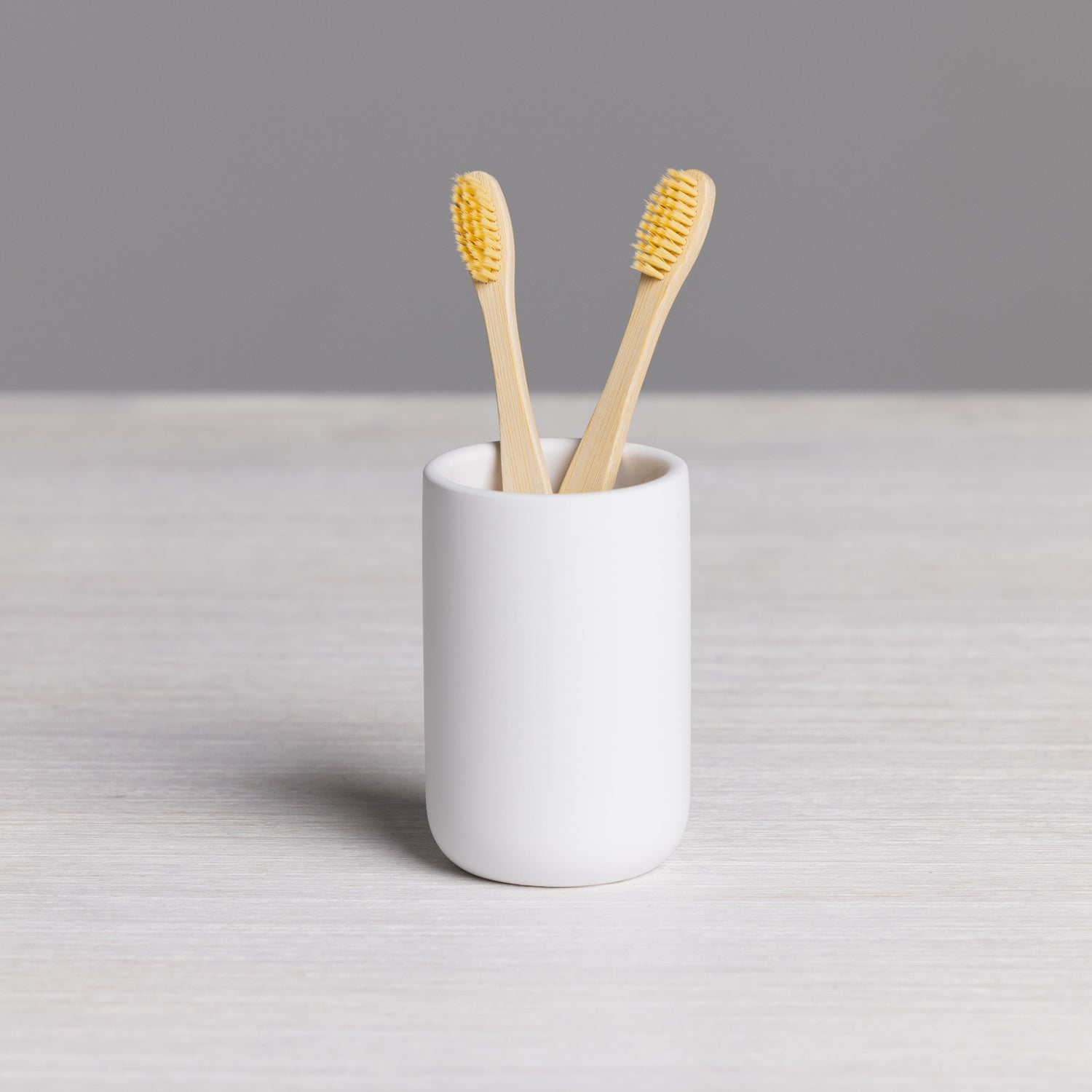 A minimalist white tumbler provides a clean and stylish holder for toothbrushes or bathroom essentials, adding a modern touch to your vanity.