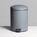 A sleek charcoal 5L pedal bin with a smooth matte finish and modern rounded design offers a stylish, practical waste solution for contemporary bathrooms.