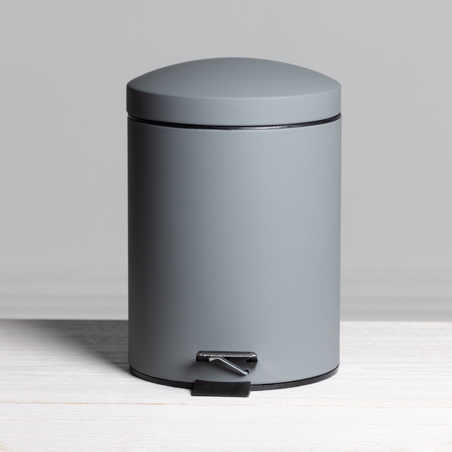 A sleek charcoal 5L pedal bin with a smooth matte finish and modern rounded design offers a stylish, practical waste solution for contemporary bathrooms.