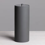 A sleek charcoal freestanding toilet roll holder with a minimalist cylindrical design and brushed metal top detail provides stylish, convenient bathroom storage.
