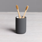 A modern charcoal tumbler with a smooth matte finish provides a stylish holder for toothbrushes or bathroom essentials, adding a sleek contemporary touch to your vanity.