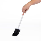 A hand holding a long-handled cleaning toilet brush with a black textured scrubber head and a white handle, shown against a plain white background.