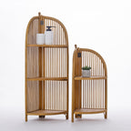 Two natural wood corner shelving units with arched slatted designs are displayed side by side, styled with simple decorative accessories to showcase their versatile storage and timeless appeal.