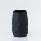 Black faceted bathroom tumbler with a modern geometric design, suitable for holding toothbrushes or rinsing.