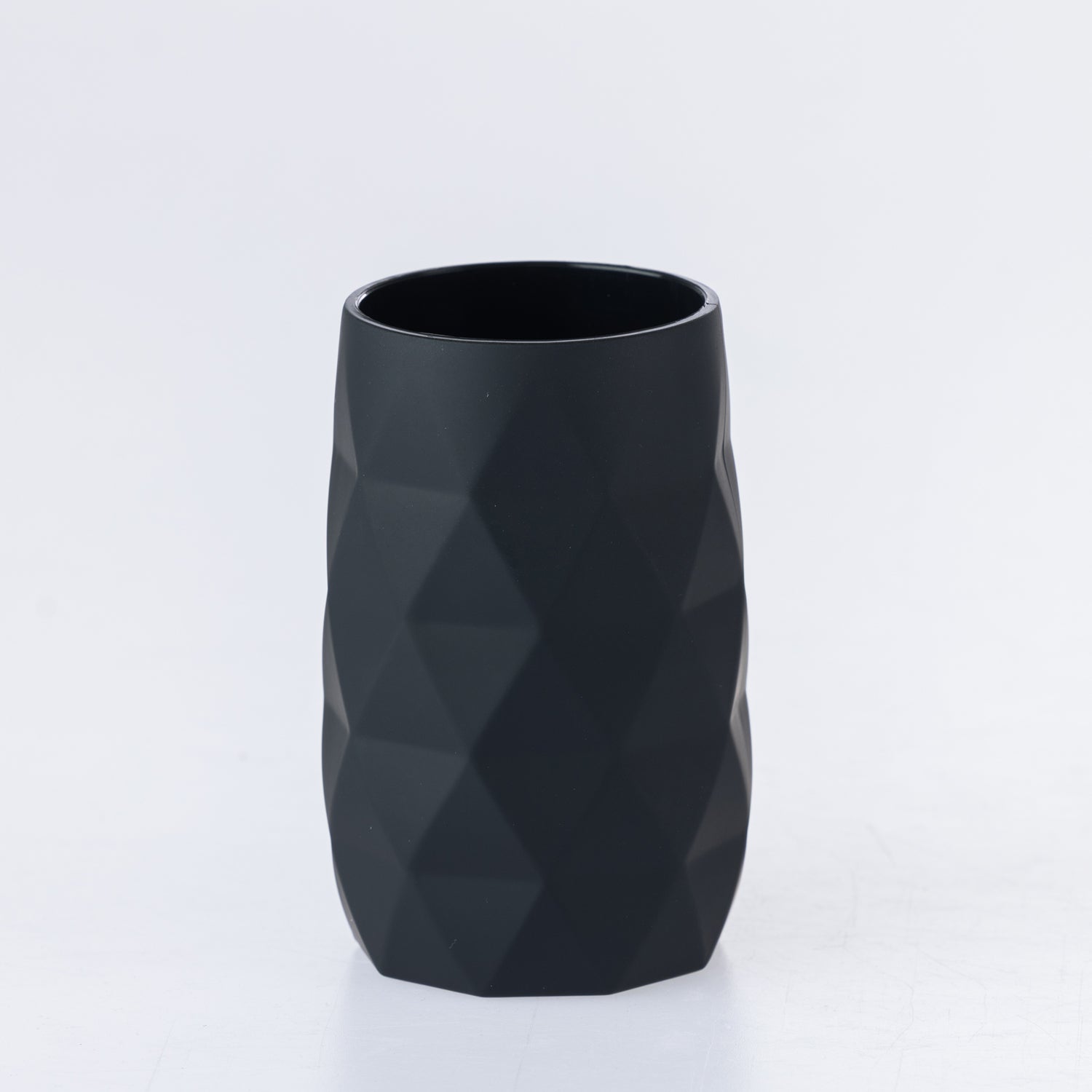 Black faceted bathroom tumbler with a modern geometric design, suitable for holding toothbrushes or rinsing.