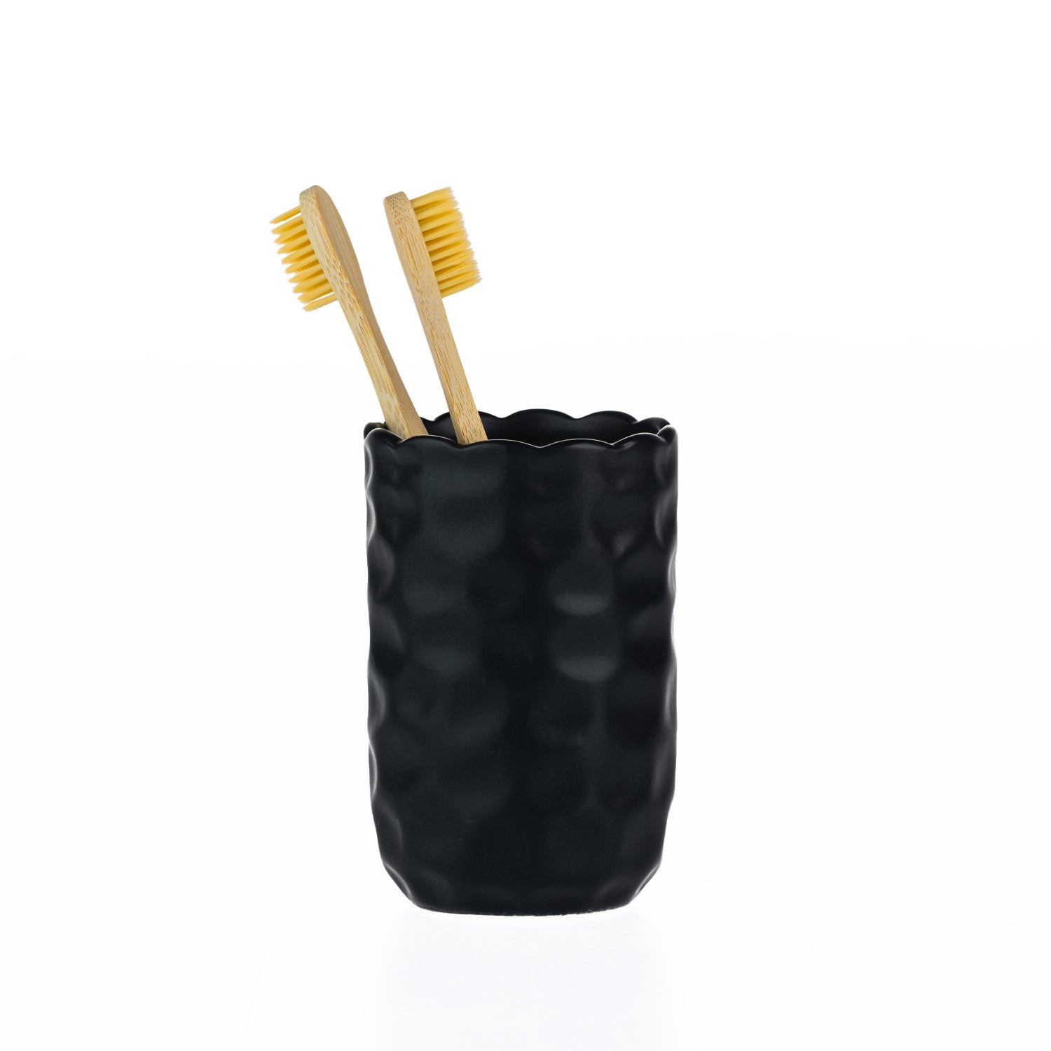 A matte black textured tumbler with a softly scalloped rim, styled with two bamboo toothbrushes.