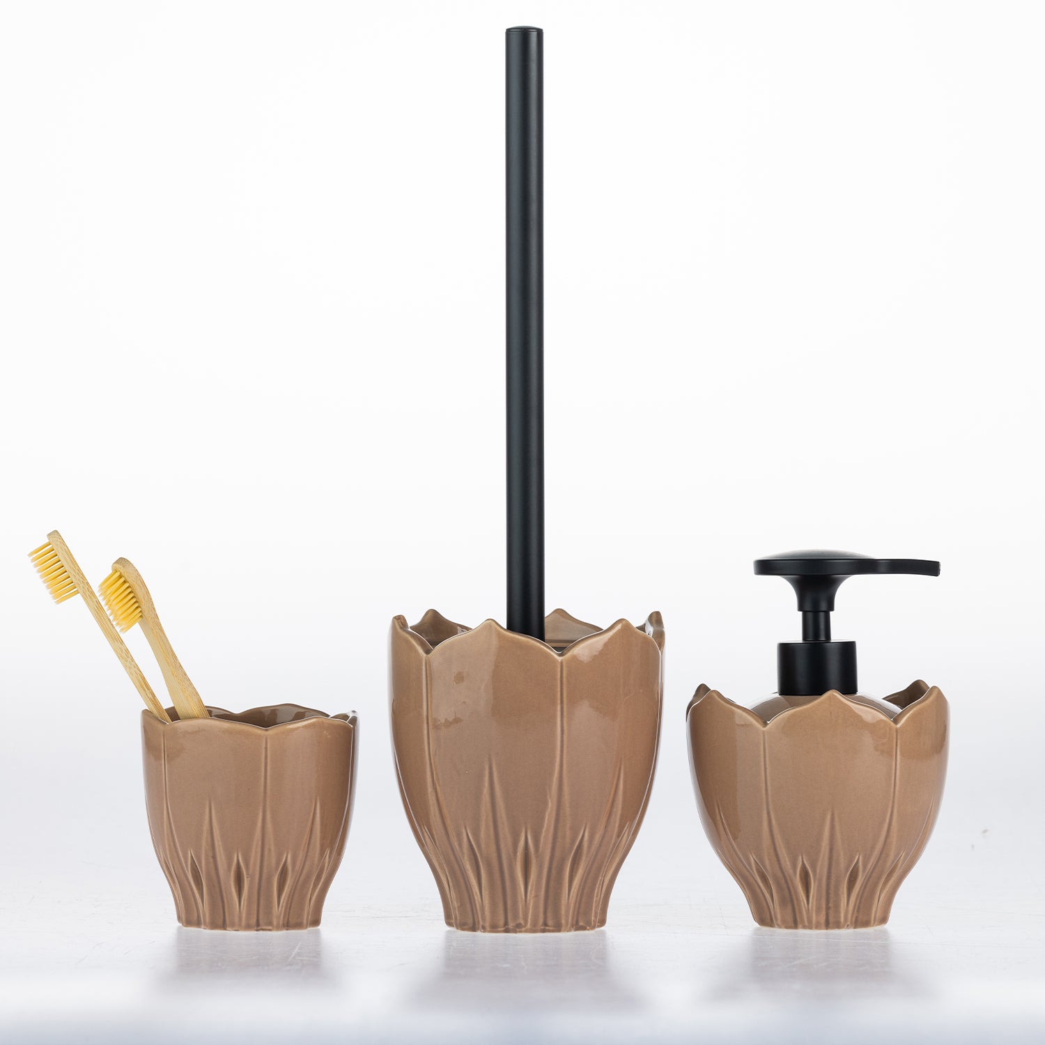 Three-piece ceramic bathroom set in a warm brown glaze, featuring a toothbrush holder with two yellow toothbrushes, a toilet brush with a black handle, and a pump dispenser with a black pump, all on a white background.