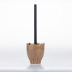 A ceramic toilet paper holder with a textured, lotus-petal-like base in a warm tan glaze, holding a black toilet paper stick, set against a clean white background.