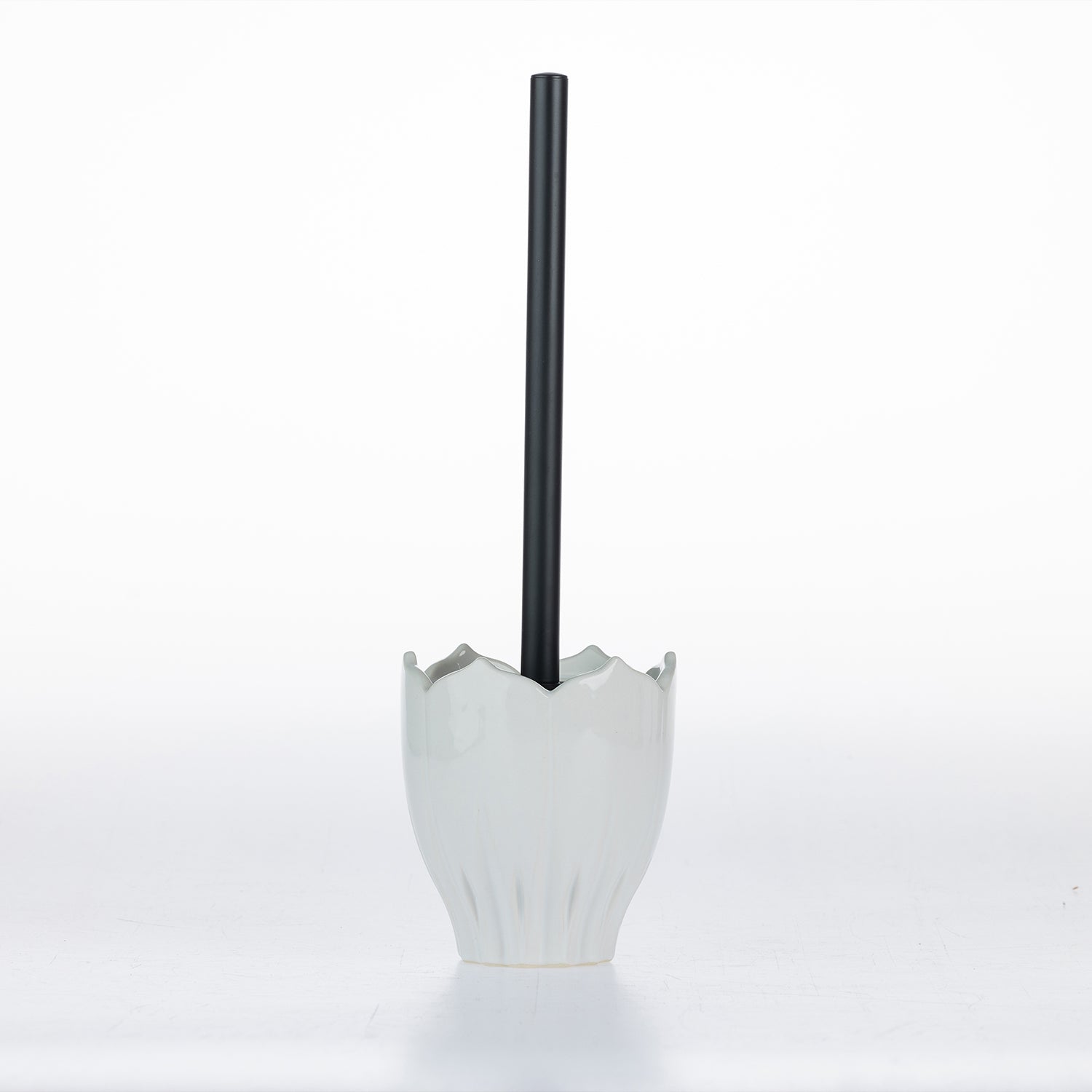 A modern white ceramic cup with a flared, lotus-like rim, holding a single black straw, set against a seamless white studio background.