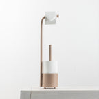A modern toilet paper holder with a curved arm holding a roll of toilet paper, a cylindrical holder with a roll of paper, and a round base, shown on a light gray surface against a white background.