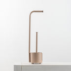 A minimalist toilet paper holder with a matching holder and a curved, modern design in a warm taupe-beige color, shown on a light gray surface against a white background.