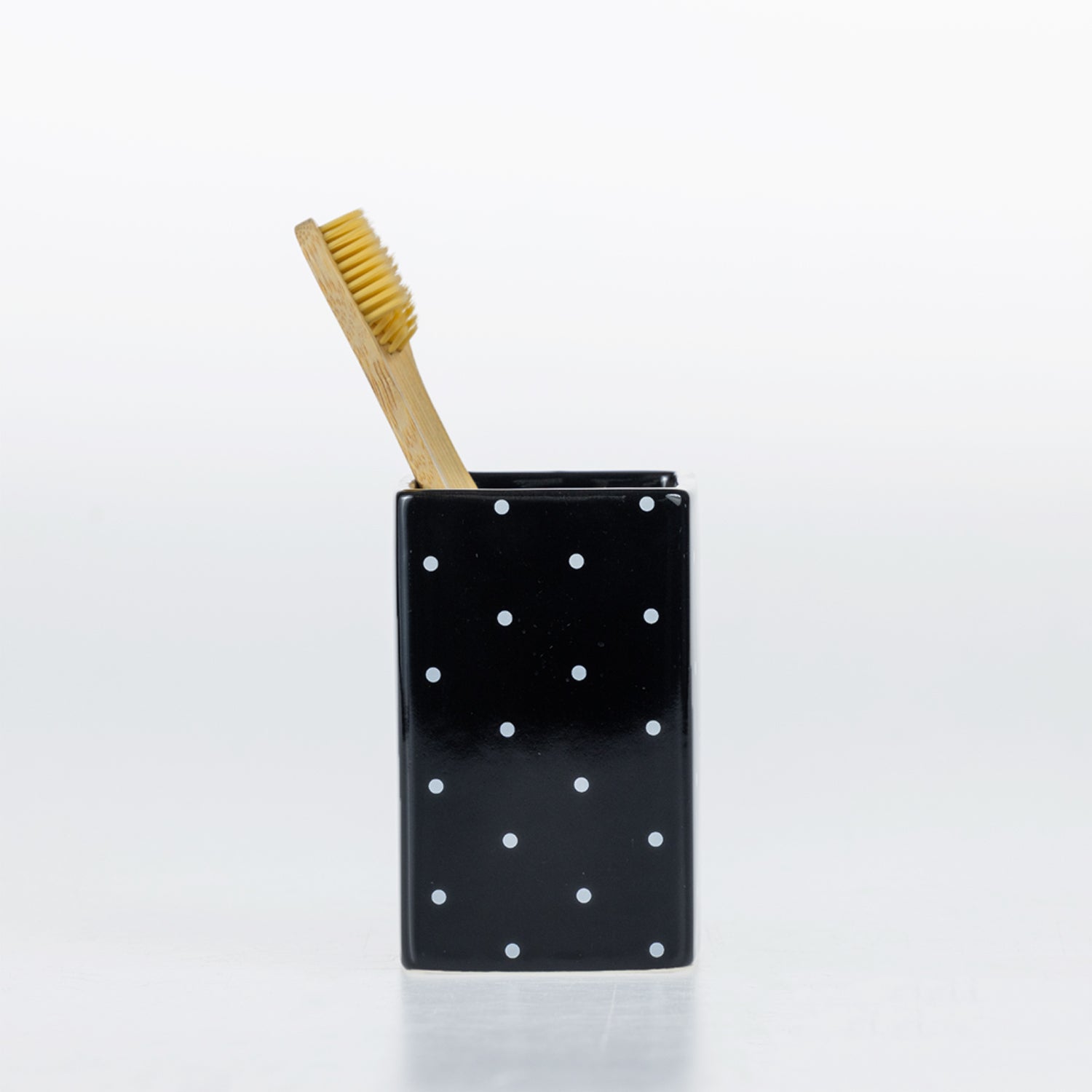 Design Republique Spotty Ceramic Tumbler in Black styled with a toothbrush to show its use as a bathroom toothbrush holder.