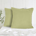 Two green pillows on a bed with a white wooden panel background