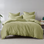 Green bedding set on a bed in a room with a plant and nightstand.
