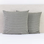 A pair of thyme and white pinstripe European pillowcases adds a relaxed, timeless touch to a neatly styled bed.
