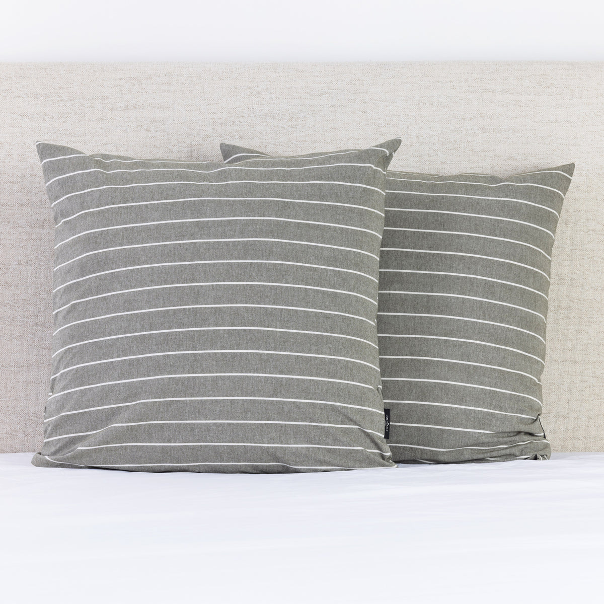 A pair of thyme and white pinstripe European pillowcases adds a relaxed, timeless touch to a neatly styled bed.