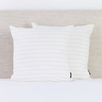 A pair of crisp white pinstripe European pillowcases brings a fresh, timeless look to a neatly styled bed.