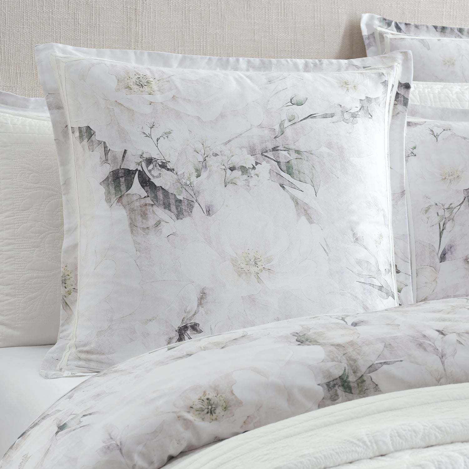 White floral bedding set with matching pillows and duvet cover, featuring a delicate gray and green watercolor-style floral print.