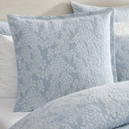 Private Collection Garden Veil European Pillowcase in Chambray styled on a bed with matching floral jacquard bedding and white quilted pillows.