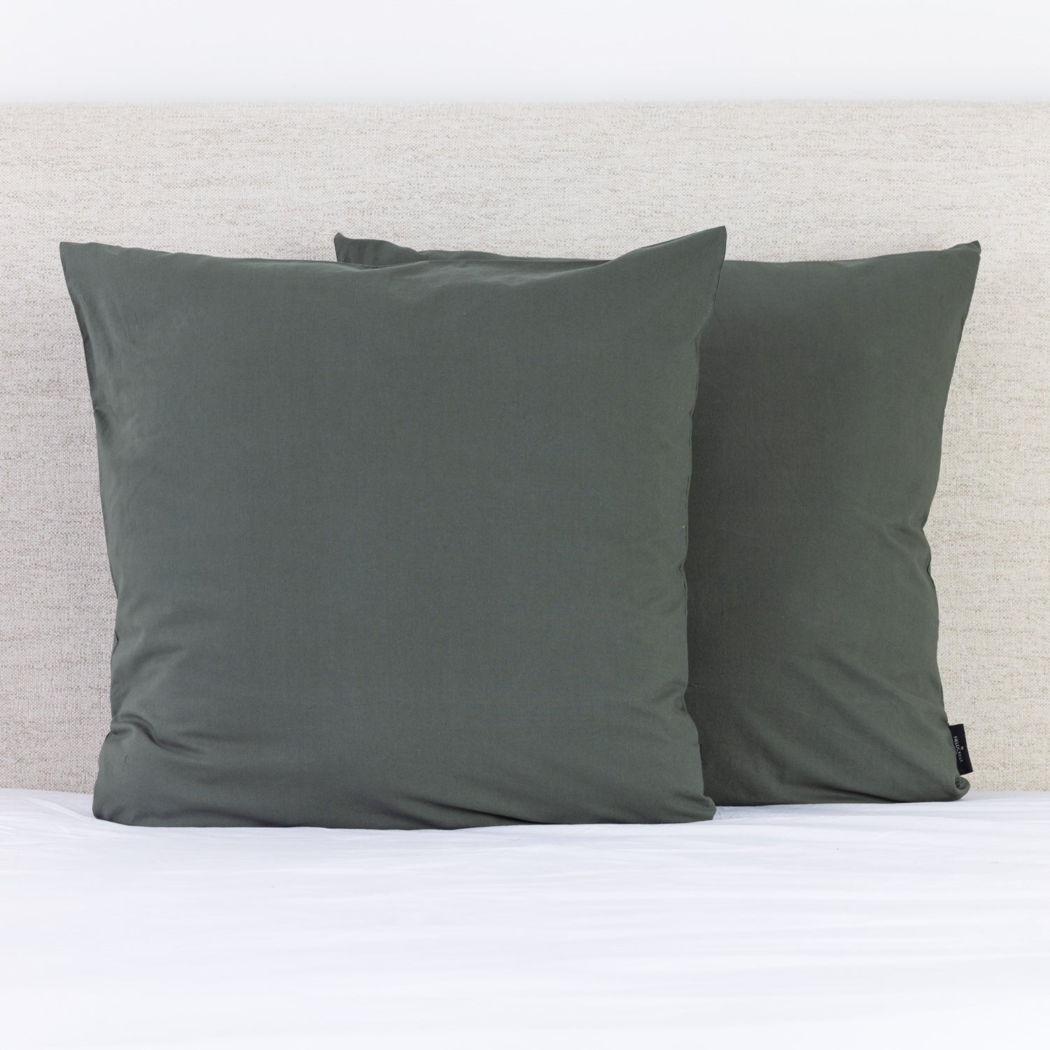 A pair of deep thyme green European pillowcases adds a rich, contemporary accent to a neatly styled bed.