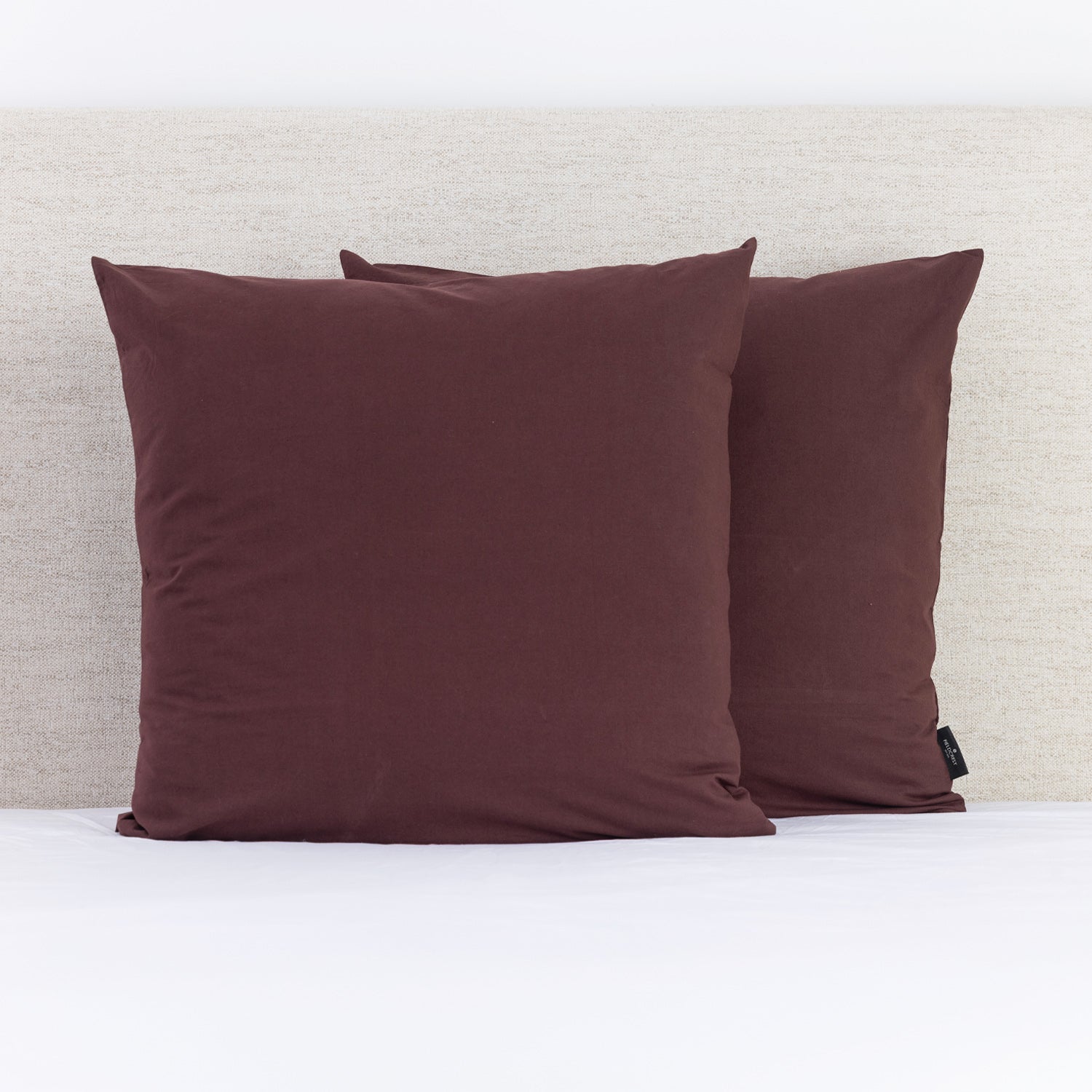 A pair of rich hazelnut European pillowcases adds a warm, sophisticated accent to a neatly styled bed.