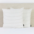 A pair of crisp white European pillowcases with fine green pinstripes adds a clean, timeless accent to a neatly styled bed.