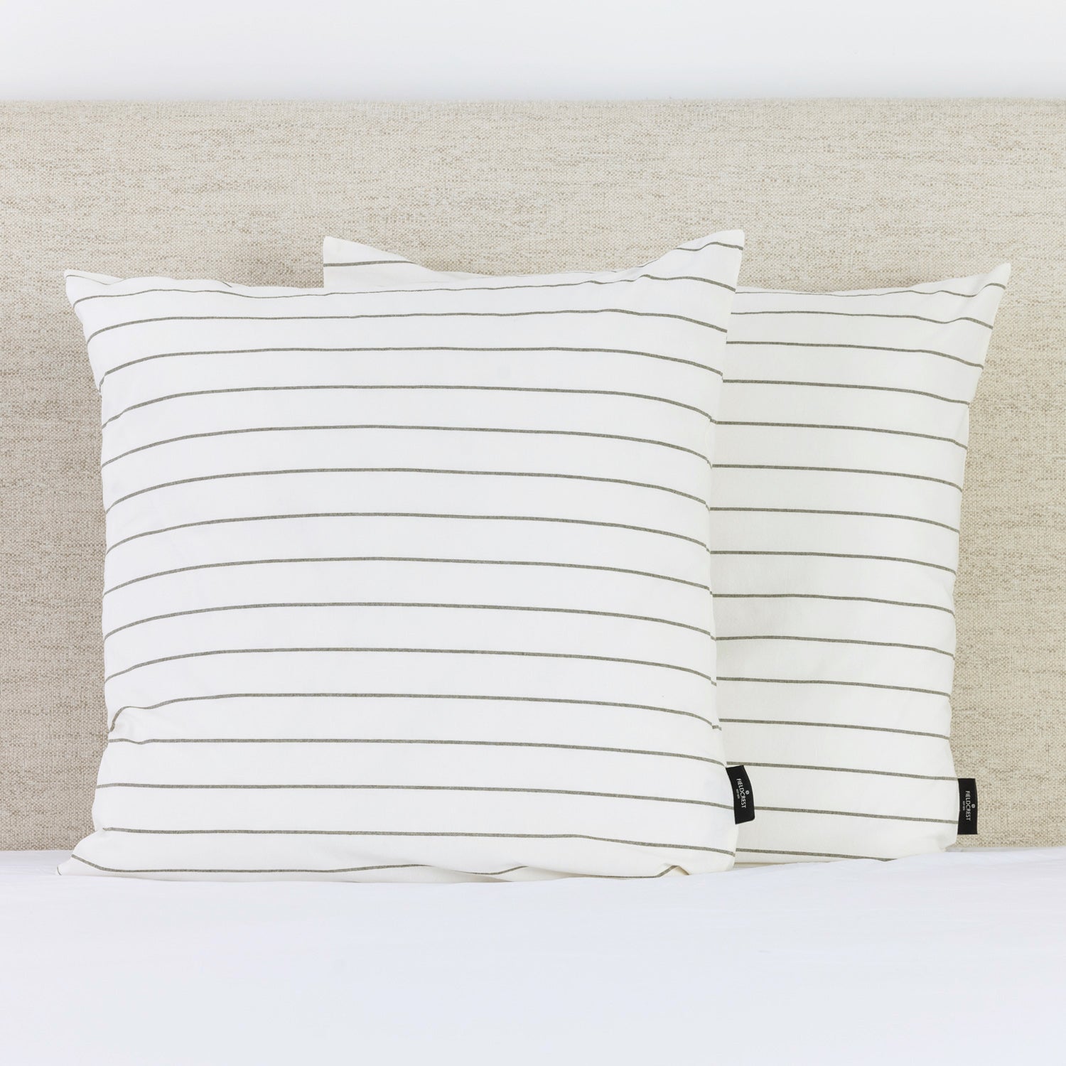 A pair of crisp white European pillowcases with fine green pinstripes adds a clean, timeless accent to a neatly styled bed.