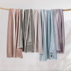 Cove Pocket Towel range displayed hanging over a rope in Mocha, Olive, Grey, Seafoam Blue and Lilac, each featuring white stripes and a zippered pocket.