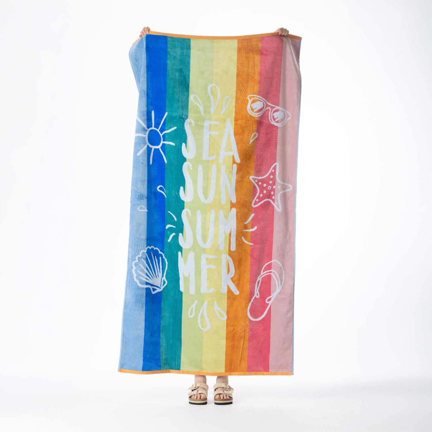 Multi-coloured striped beach towel featuring “SEA SUN SUMMER” text with playful summer-inspired motifs, held up against a white background.