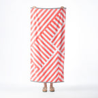 Orange and white beach towel featuring a bold geometric stripe design with contrasting black and white striped borders, held up against a white background.