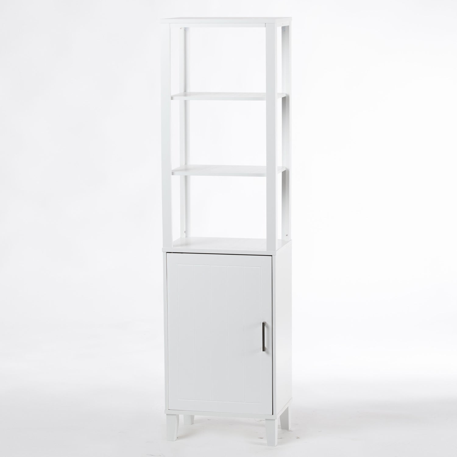 A tall white bathroom shelving unit with three open display shelves, a paneled cupboard, and a brushed metal handle offers a stylish combination of open and concealed storage.