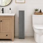 Grey slim bathroom cabinet placed between a wooden vanity and white toilet in a modern bathroom.