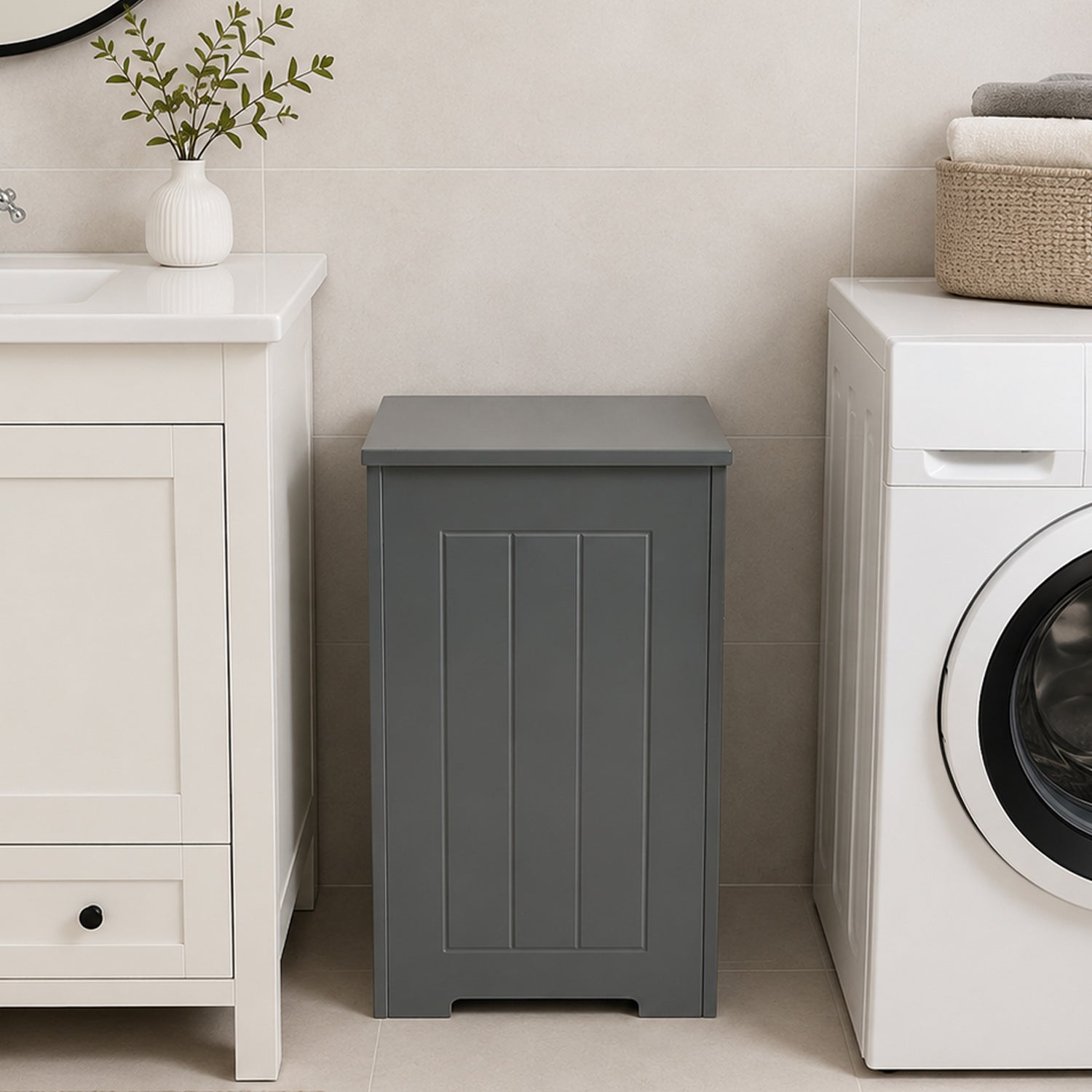 Grey laundry hamper placed between a white vanity and washing machine in a modern bathroom.