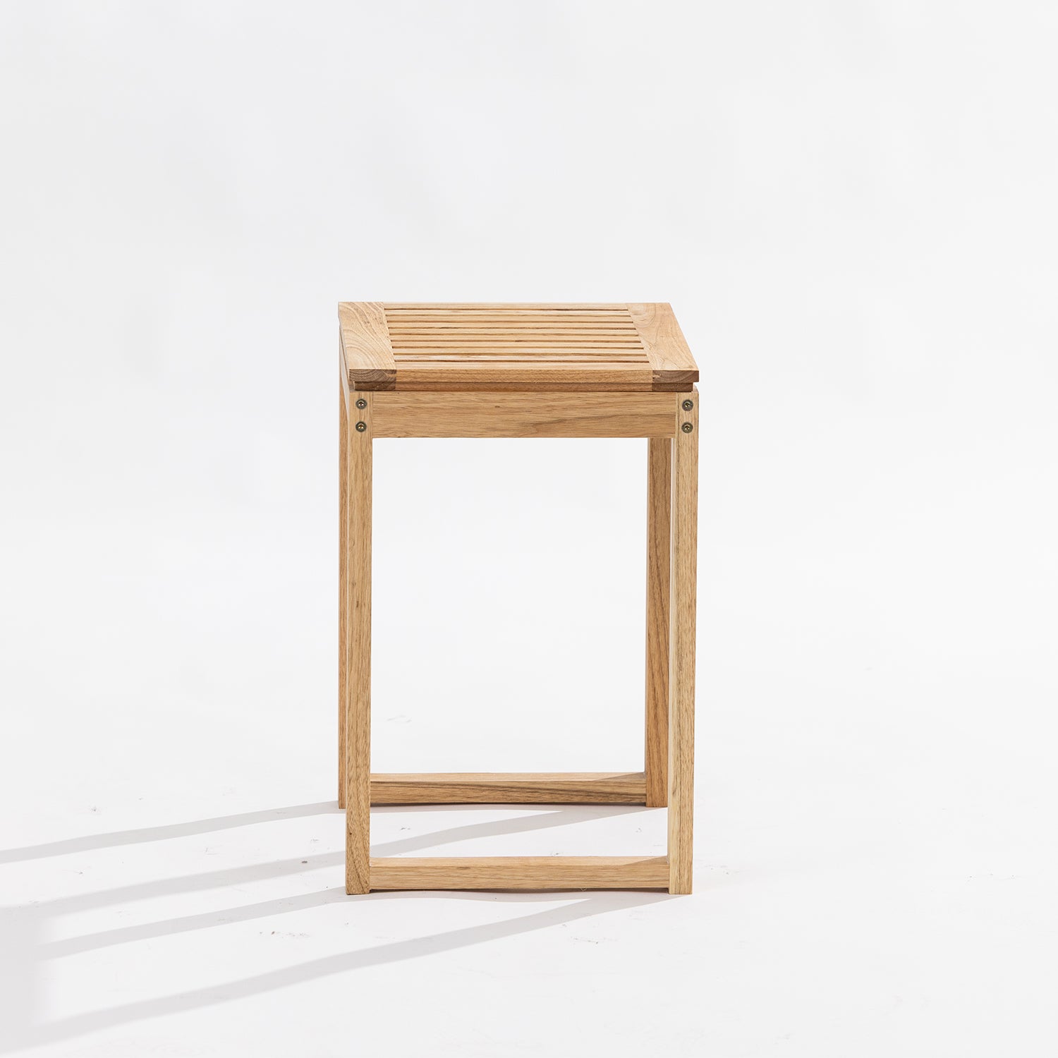 A minimalist wooden side table or stool with a light oak finish, featuring a slatted top and open geometric frame, photographed on a clean white studio background.