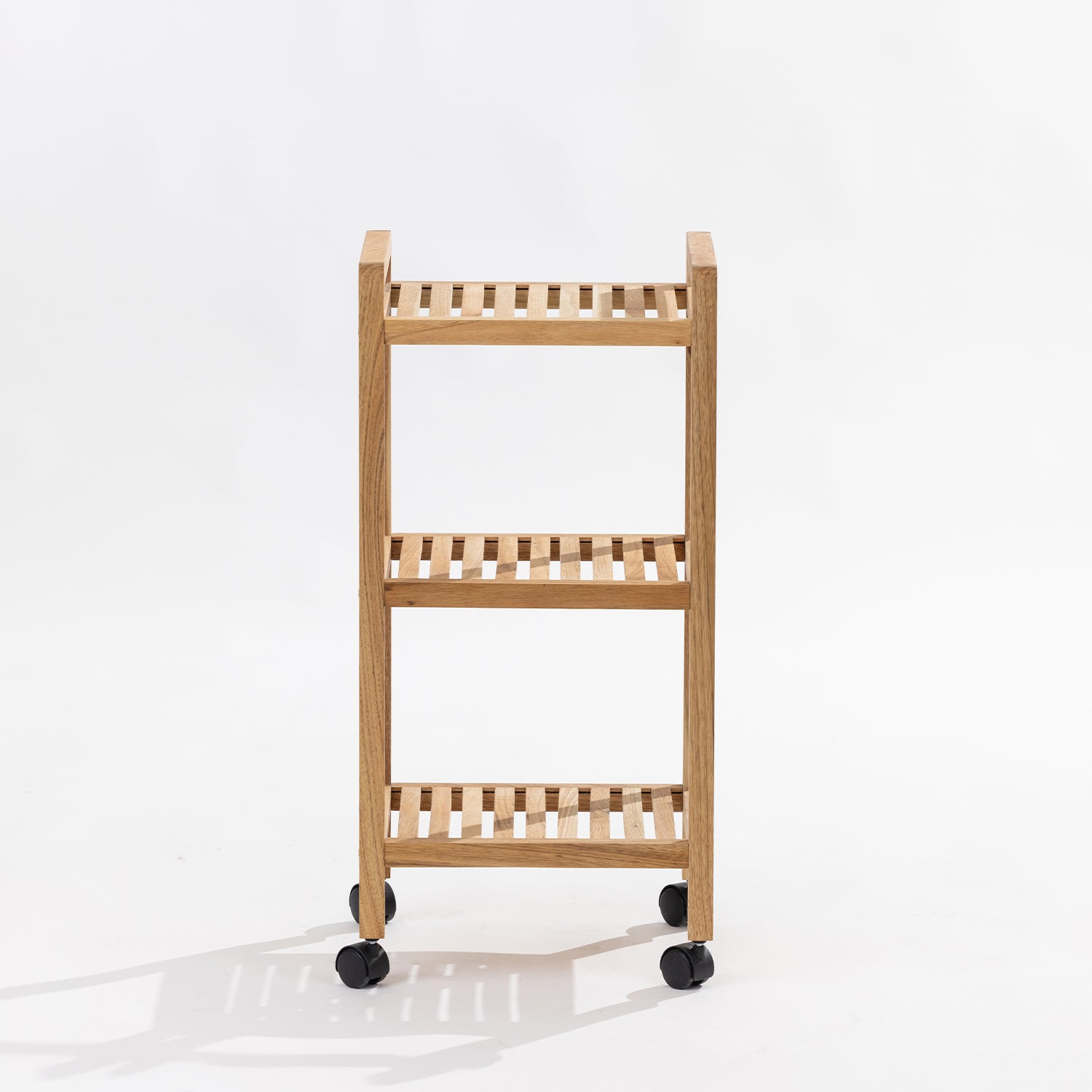 A three-tier wooden rolling shelf cart with black caster wheels, photographed against a clean white studio background.
