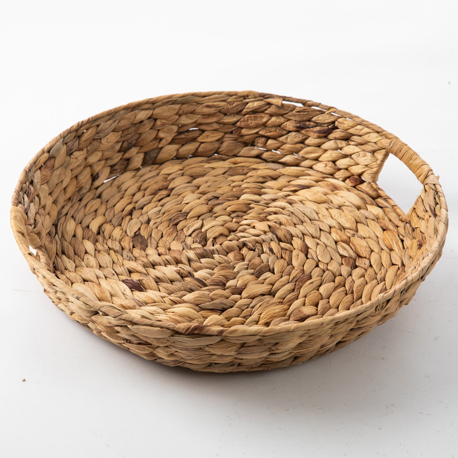 Round natural water hyacinth woven tray with integrated side handles and a braided textured finish.